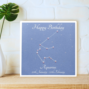 Aquarius StarSign card with printed dates and crystals displayed on a wooden shelf in front of a white wall