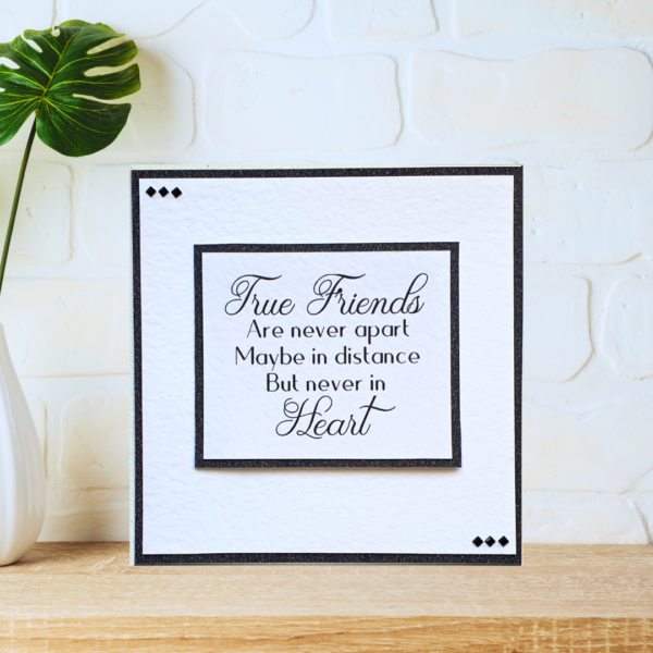 Black and white layered friendship quote card with beautiful crystals displayed on a wooden shelf in front of a white wall