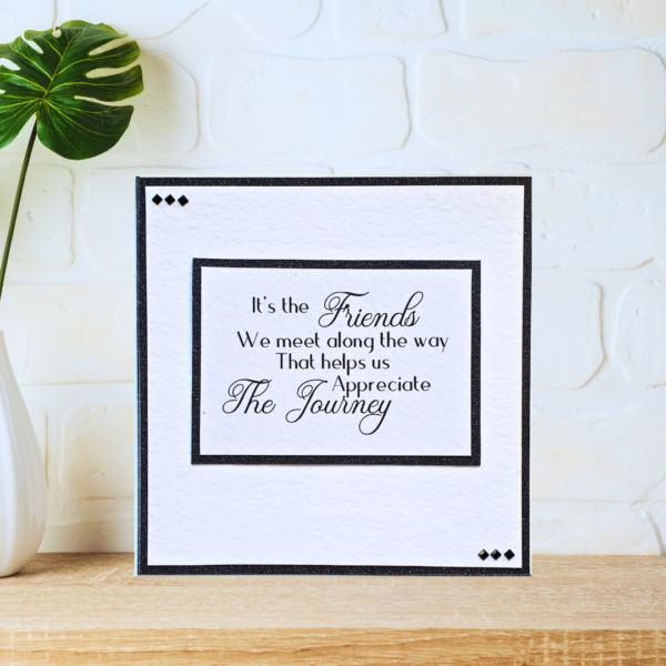 Black and white layered friendship quote card with beautiful crystals displayed on a wooden shelf in front of a white wall