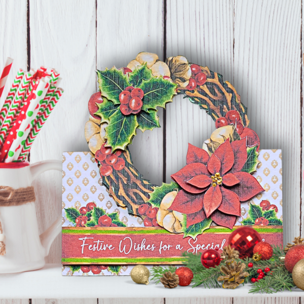 A white shef in fromt of white panellled wall with a willow wreath. The wreath is decorated with a poinsettia and holly sprig with berries.