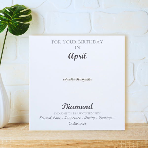 Diamond April Birthstone card displayed on a wooden shelf in front of a white wall.