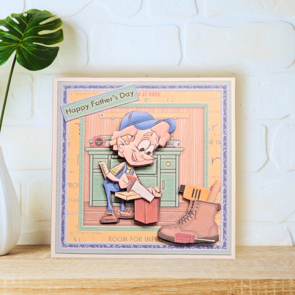 Cute DIY Guys - Carpenter multi layered Birthday Card displayed on a wooden shelf in front of a white brick wall.
